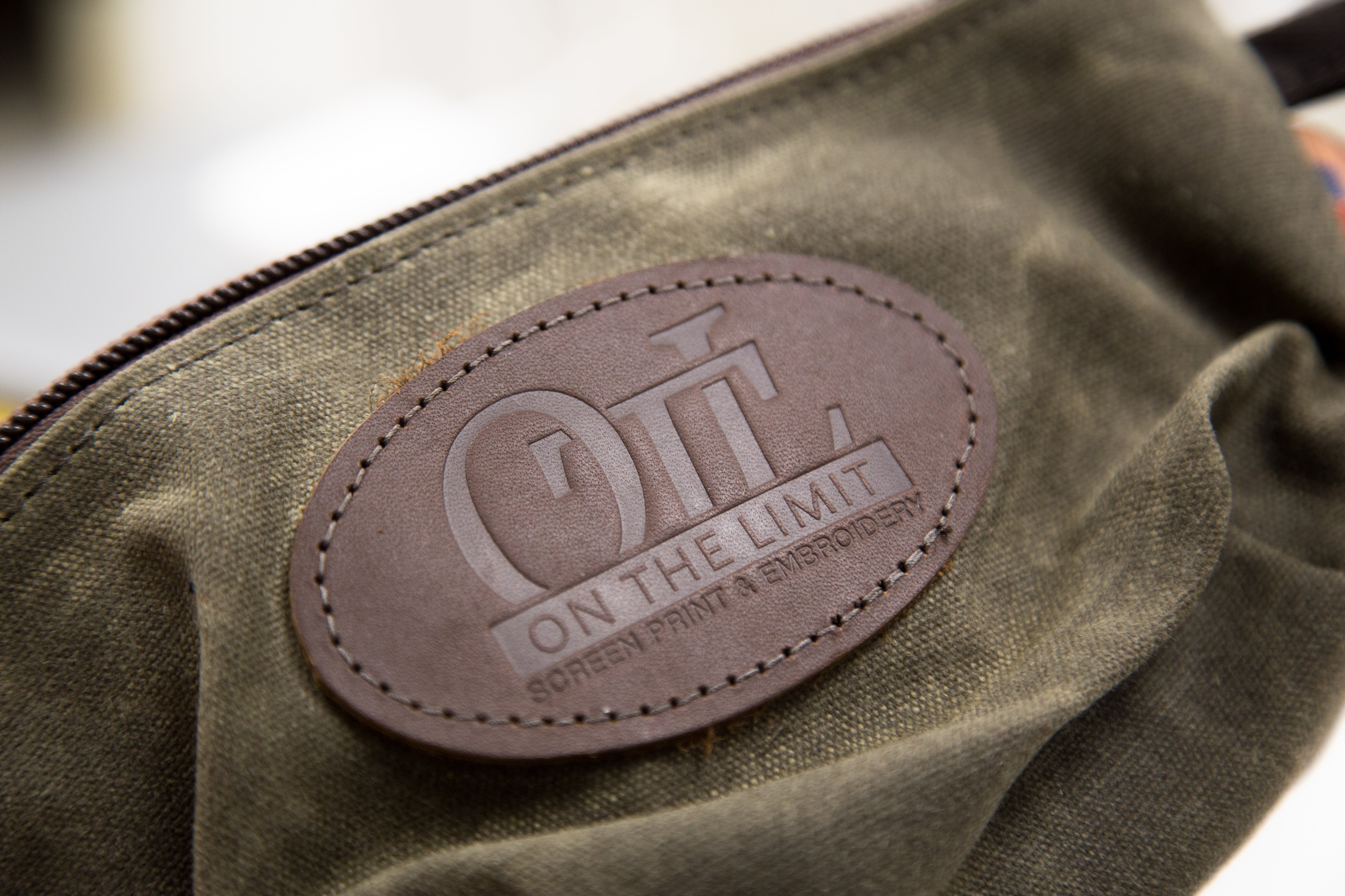 On The Limit branded leather patch on a Frost River accessory bag.